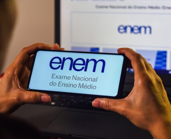 Imagem de pessoa segurando um telefone com a logo do Enem - Metrópoles